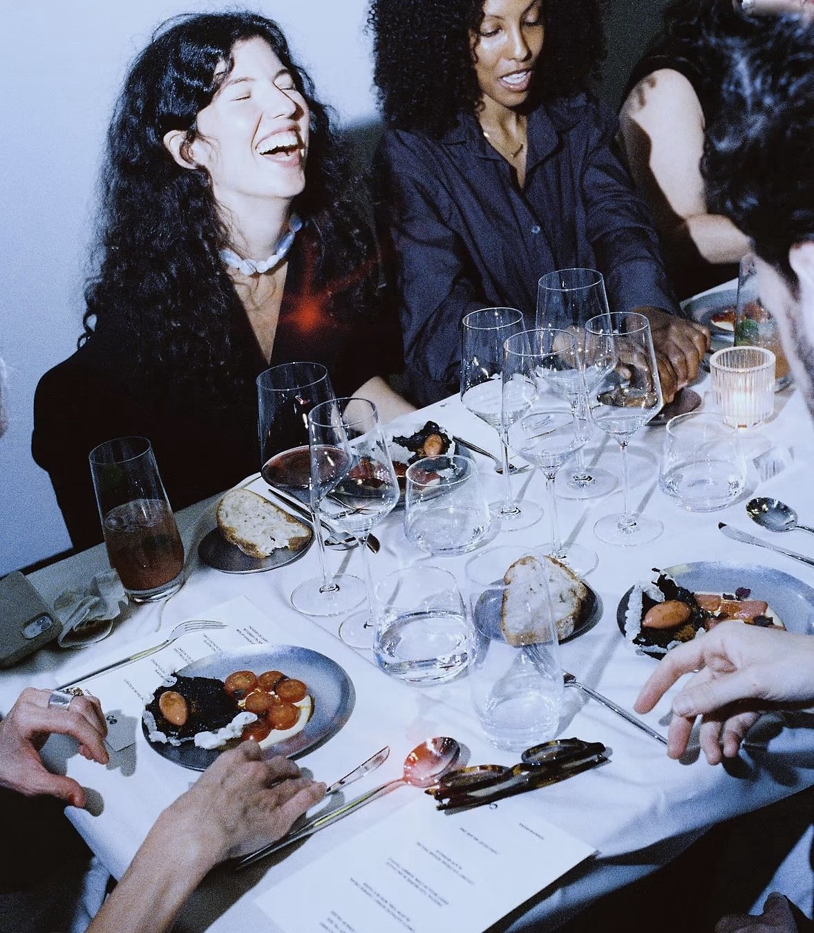 Guests laughing around a dinner table at a Secret Supper 404 event