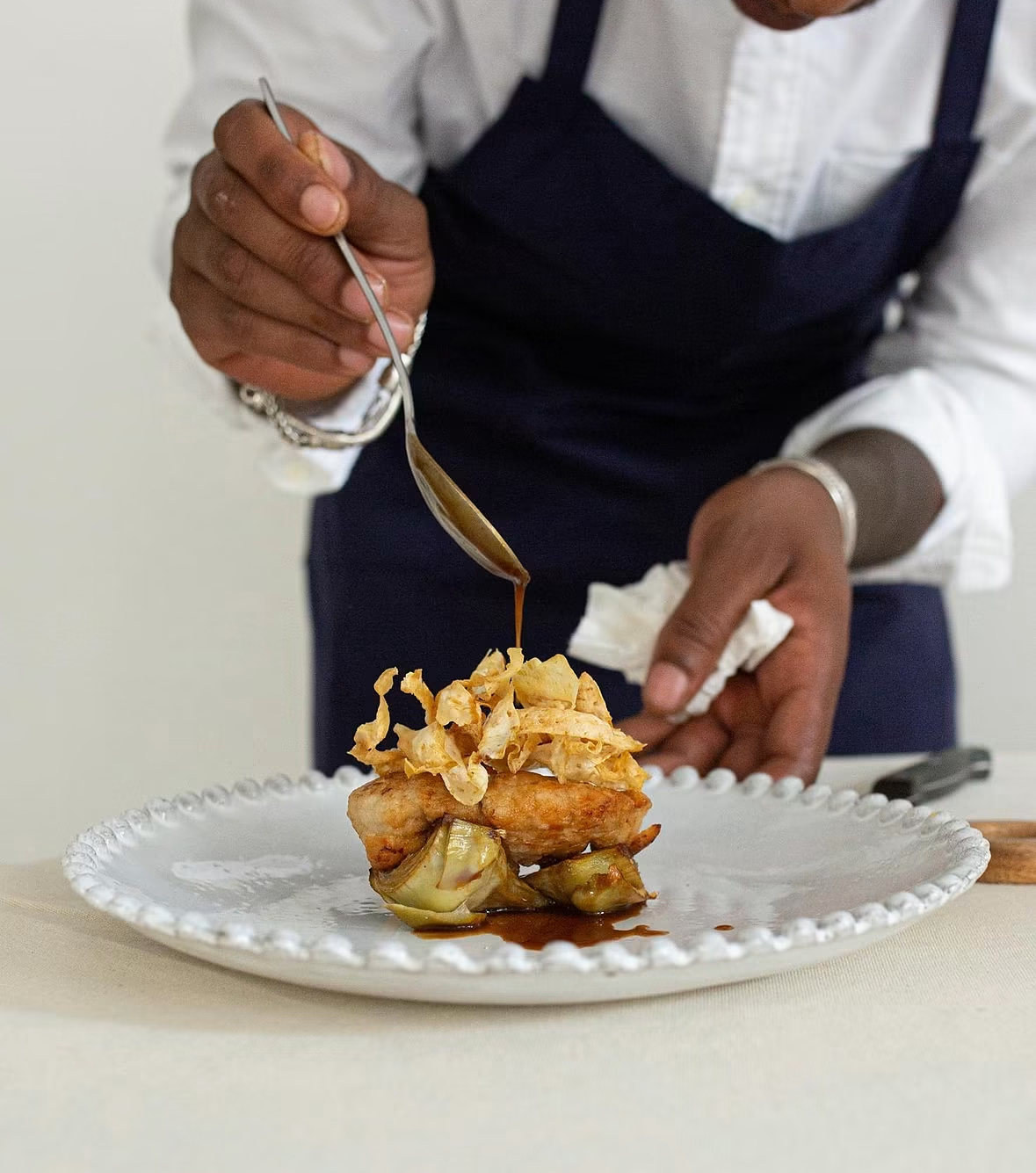 Chef spooning sauce over a plated entrée at Secret Supper 404 in Atlanta